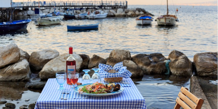 an image of a dinner table for two by the sea harbour in Sorrento, Italy
