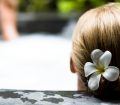 A woman with a flower in her hair relaxing on the side of a jacuzzi