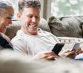 Mature couple sat on sofa smiling with phones