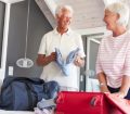 senior couple smiling while packing suitcase