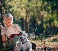 senior woman reading outdoors with dog