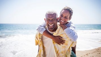 an image of a couple on the beach, with one giving the other a piggyback