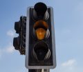 an image of a traffic light on amber with a blue sky in the background
