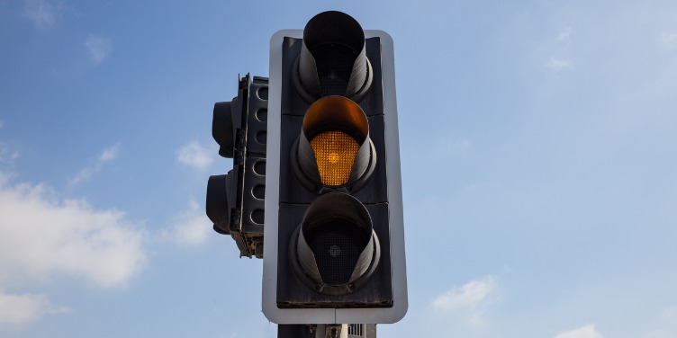 an image of a traffic light on amber with a blue sky in the background