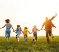 Family holding hands running on a field in summer