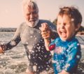 Child playing in the sea with family member
