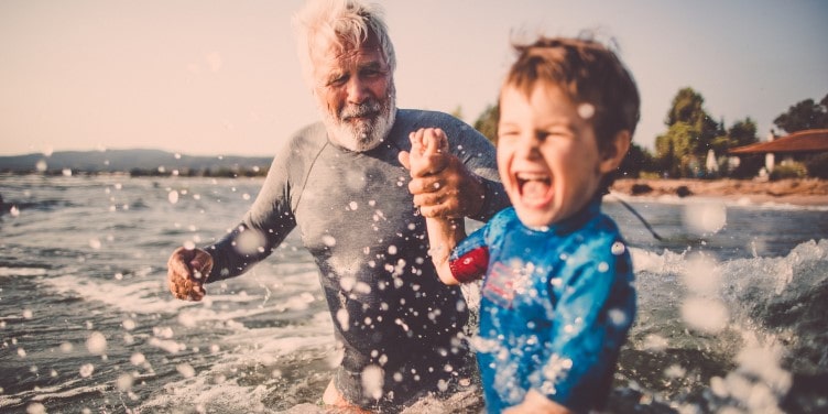 Child playing in the sea with family member
