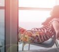 Woman relaxes in chair on the balcony of a cruise ship