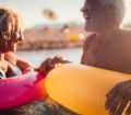 Older couple on holiday having fun in the sea with colourful inflatable rings