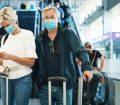 A couple waiting for a delayed flight in a busy airport wearing masks
